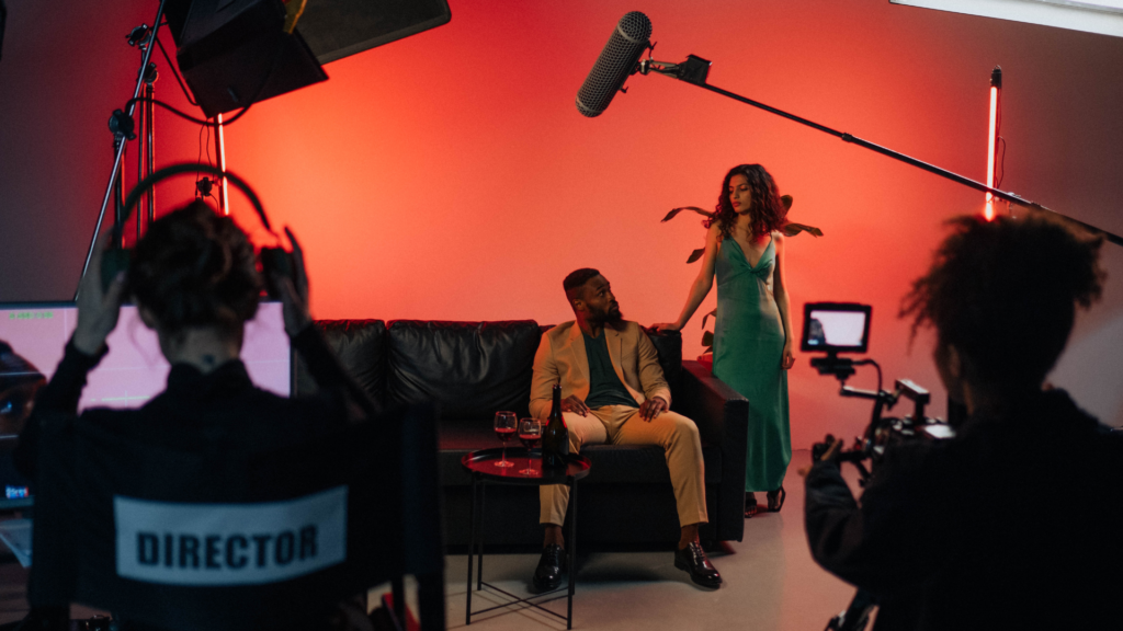 An actor delivering lines on set, with the film crew working in the background at a movie shoot location.