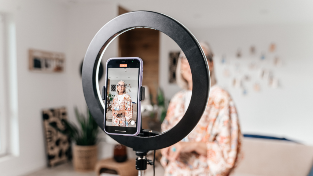 A woman recording a video testimonial on her camera, smiling confidently as she shares her positive experience, capturing authentic feedback to be used for marketing on websites, social media, and email newsletters.